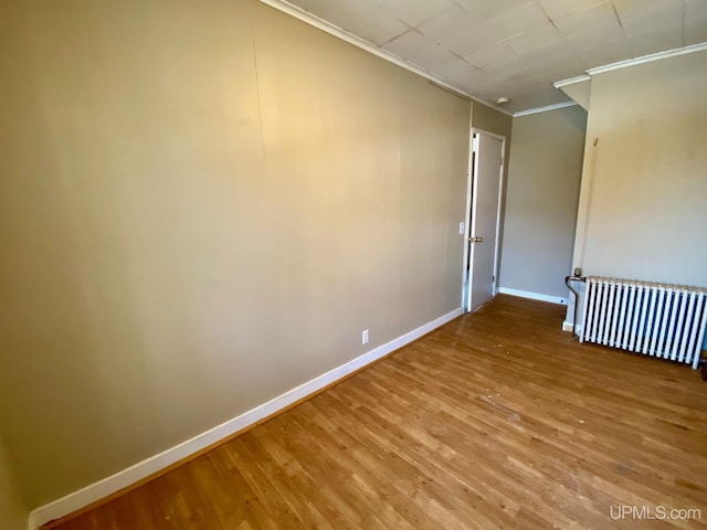 unfurnished room with radiator, wood-type flooring, and ornamental molding