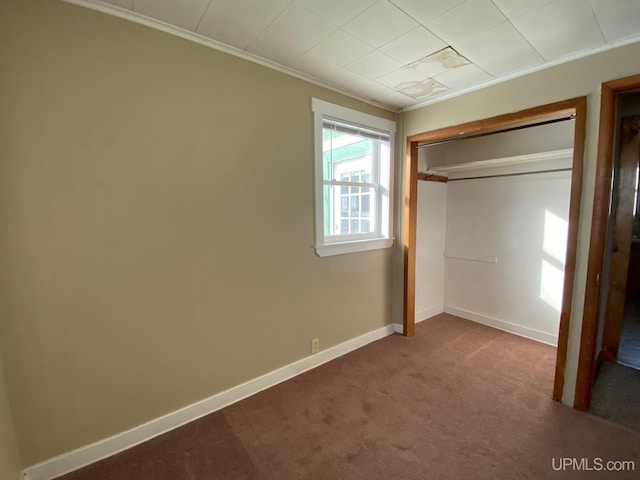 unfurnished bedroom featuring ornamental molding, carpet floors, and a closet