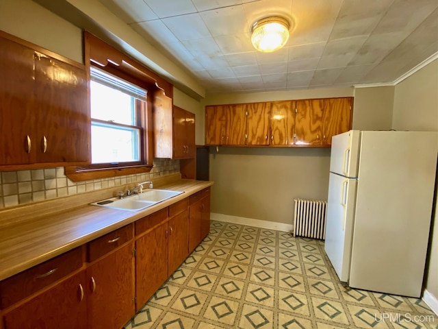 kitchen with white refrigerator, radiator, sink, and decorative backsplash