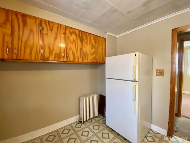 kitchen with radiator heating unit, ornamental molding, and white fridge