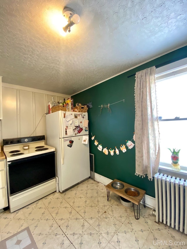 kitchen with radiator, a textured ceiling, white cabinets, and white appliances