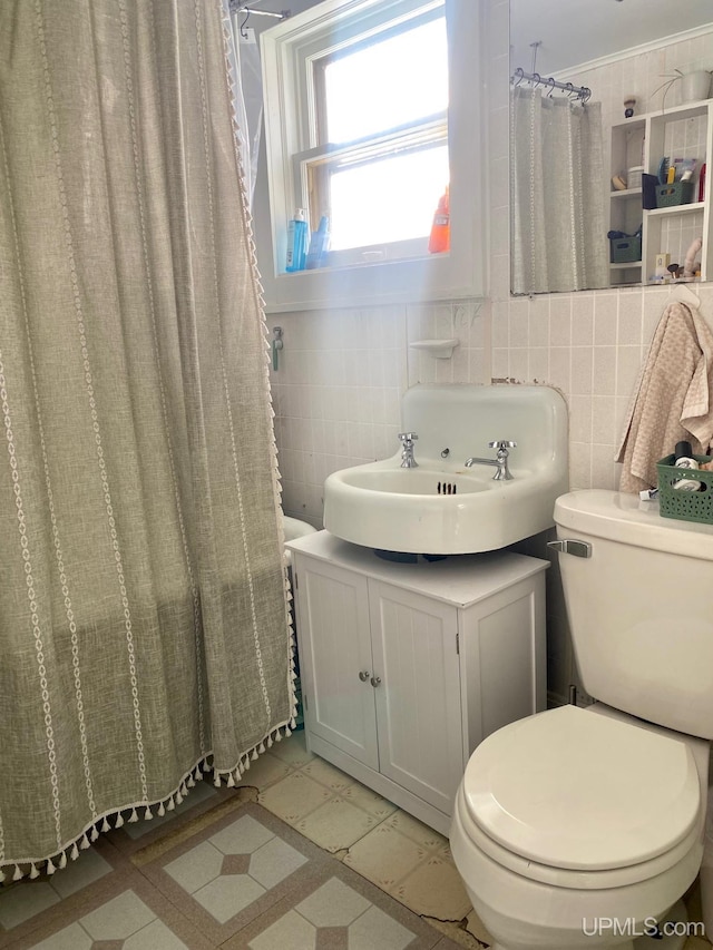 bathroom with vanity, toilet, and tile walls