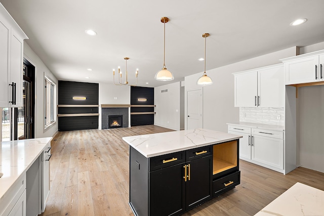 kitchen with white cabinetry, a center island, hanging light fixtures, and light hardwood / wood-style flooring