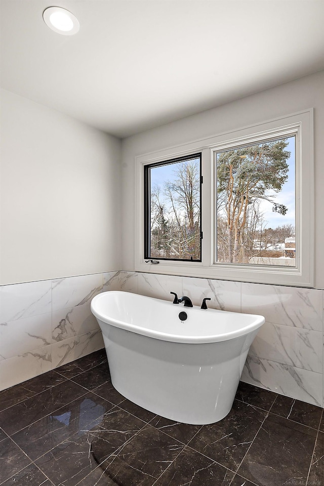 bathroom featuring plenty of natural light, tile walls, and a washtub