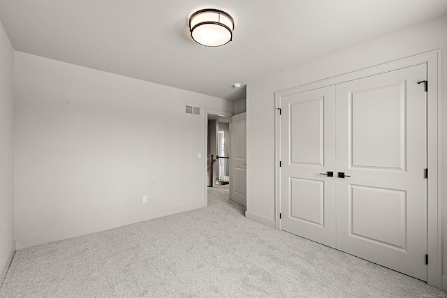 unfurnished bedroom with light colored carpet and a closet