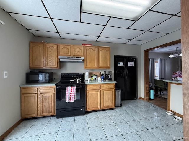 kitchen with light tile patterned flooring, a chandelier, a drop ceiling, and black appliances