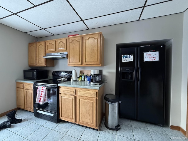 kitchen featuring a drop ceiling, light tile patterned floors, and black appliances