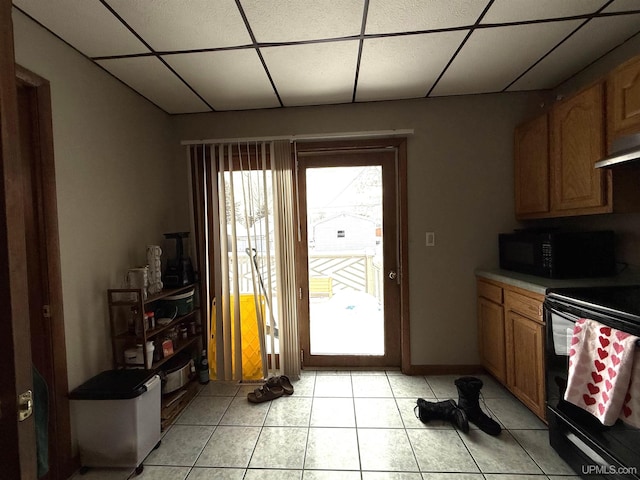 kitchen featuring light tile patterned flooring, a drop ceiling, and black appliances