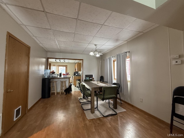 dining room featuring an inviting chandelier, hardwood / wood-style floors, and a drop ceiling