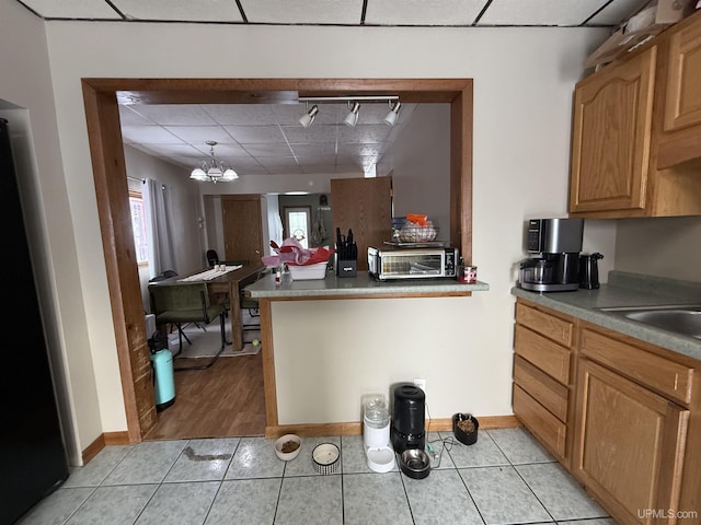 kitchen featuring a drop ceiling, sink, a notable chandelier, and light tile patterned flooring