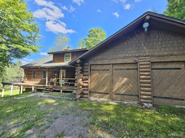 exterior space featuring a wooden deck, a garage, and a lawn