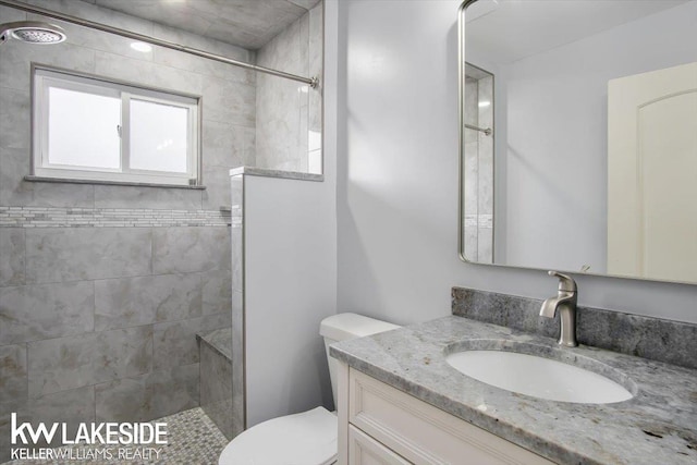 bathroom with vanity, a tile shower, and toilet