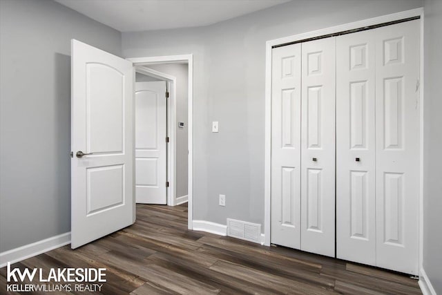 unfurnished bedroom featuring dark wood-type flooring and a closet