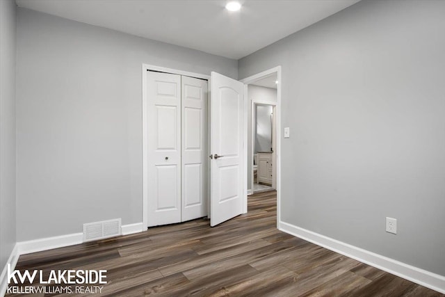 unfurnished bedroom featuring dark hardwood / wood-style flooring and a closet