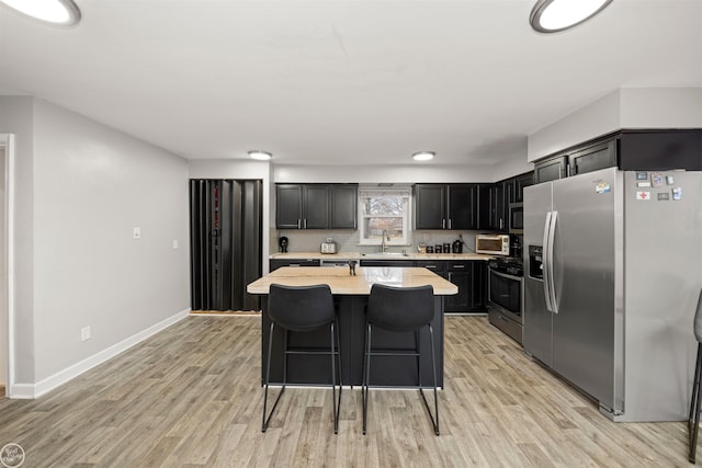 kitchen featuring a kitchen bar, light hardwood / wood-style flooring, sink, and appliances with stainless steel finishes