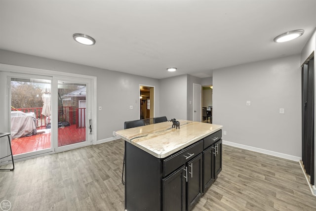 kitchen featuring a kitchen island, a breakfast bar area, light stone counters, and light hardwood / wood-style floors