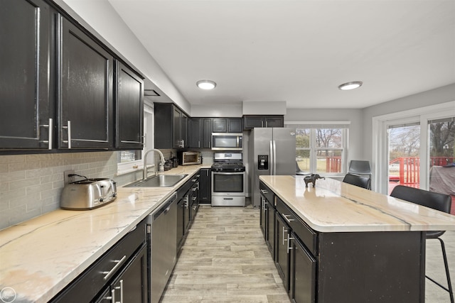 kitchen with a breakfast bar, sink, a kitchen island, stainless steel appliances, and backsplash