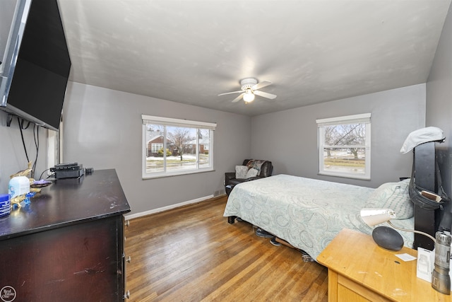 bedroom featuring ceiling fan, wood-type flooring, and multiple windows