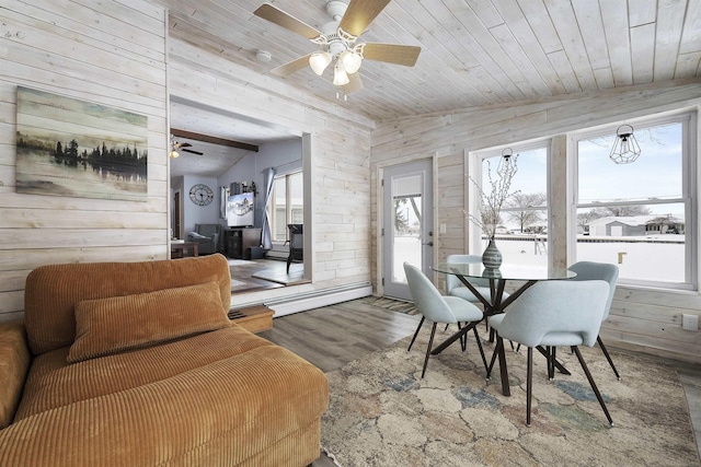 dining room with wood walls, wooden ceiling, a wealth of natural light, and a baseboard heating unit