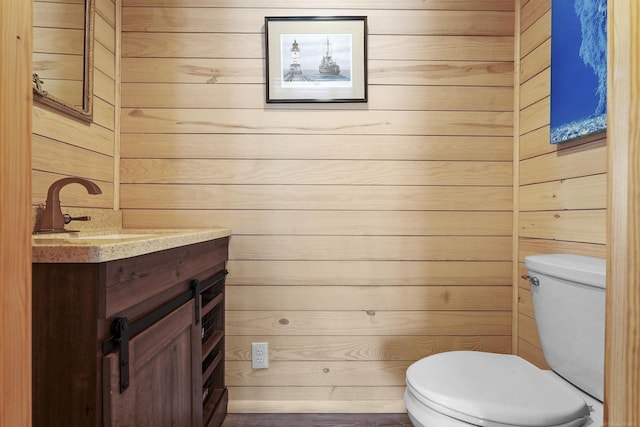 bathroom with vanity, wooden walls, and toilet