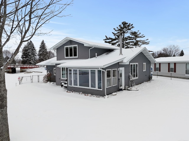 snow covered house featuring a sunroom