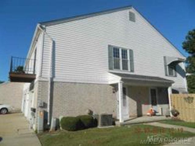 view of side of property with cooling unit and a lawn