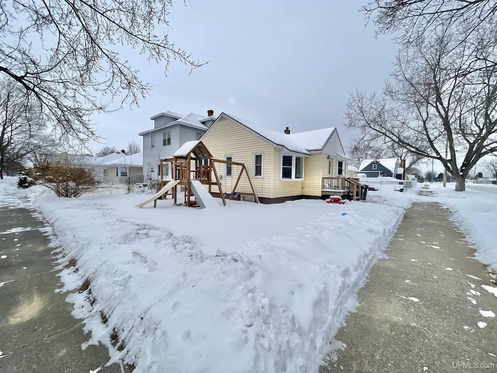 snow covered rear of property with a playground