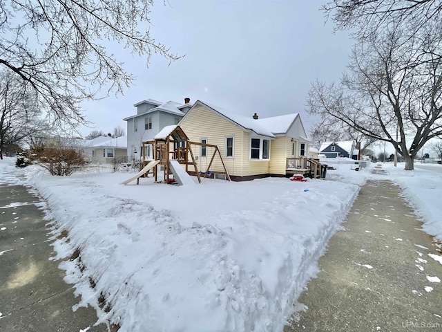 snow covered rear of property with a playground