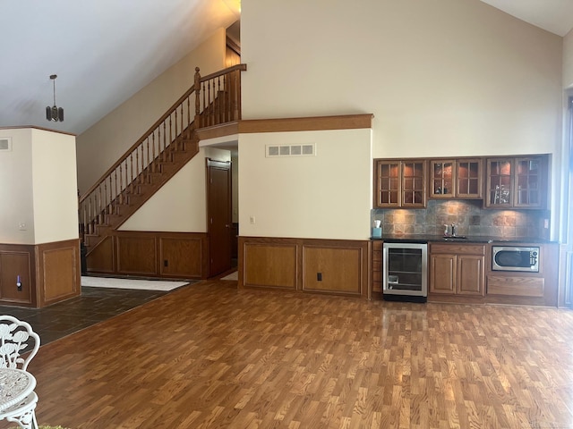 unfurnished living room with a high ceiling, dark hardwood / wood-style floors, and beverage cooler