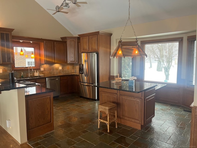 kitchen featuring tasteful backsplash, hanging light fixtures, stainless steel appliances, and dark stone countertops