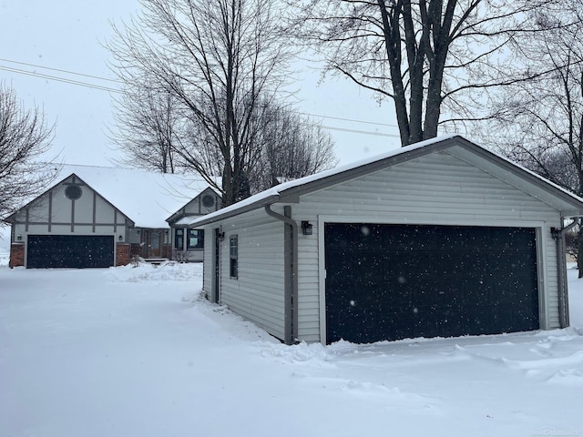 snow covered garage featuring a detached garage