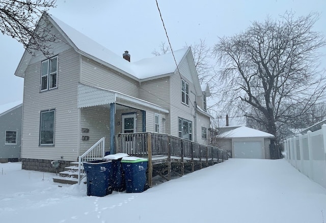 snow covered property featuring a garage and an outdoor structure