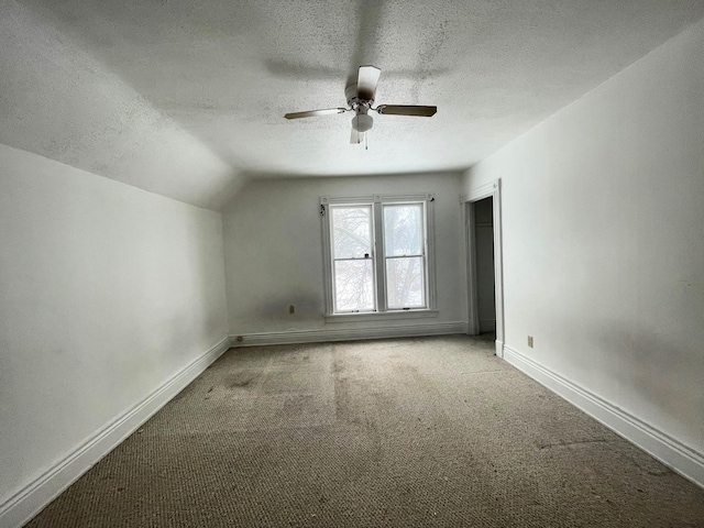 bonus room featuring ceiling fan, vaulted ceiling, light colored carpet, and a textured ceiling