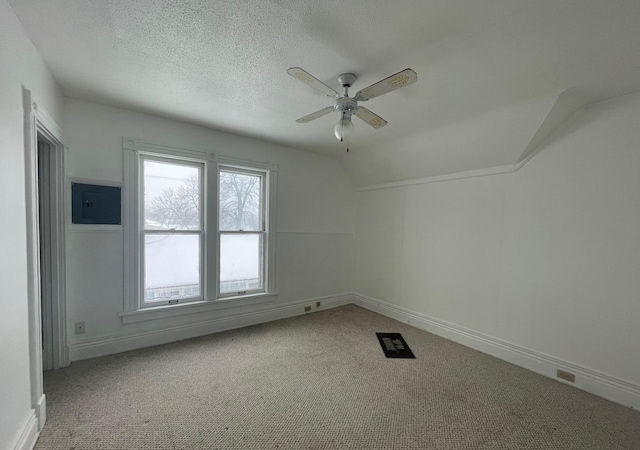 carpeted empty room featuring ceiling fan, vaulted ceiling, and a textured ceiling