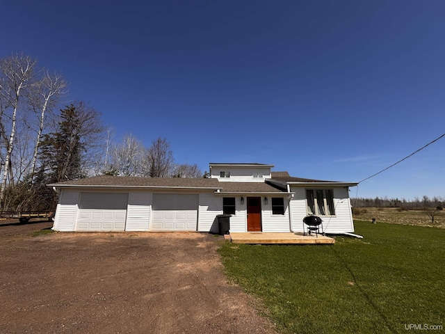 view of front of house featuring dirt driveway, a front yard, and an attached garage