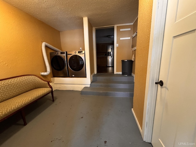 laundry area with washing machine and dryer and a textured ceiling