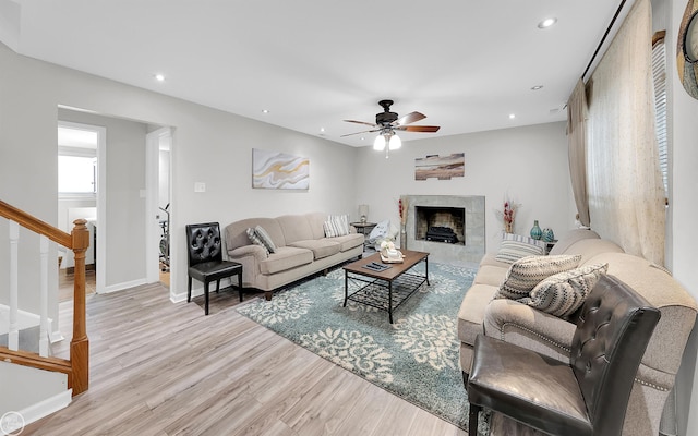 living room featuring a fireplace, light hardwood / wood-style floors, and ceiling fan