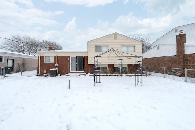 snow covered rear of property with a gazebo and central AC unit