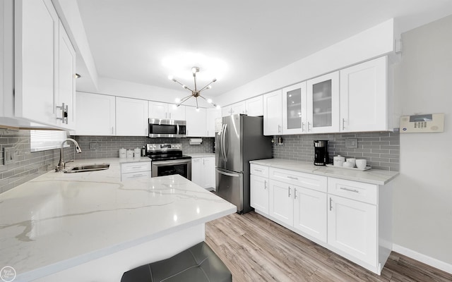 kitchen featuring white cabinetry, stainless steel appliances, sink, and light stone counters