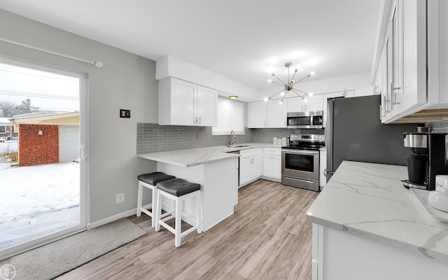 kitchen with light stone counters, sink, white cabinets, and appliances with stainless steel finishes