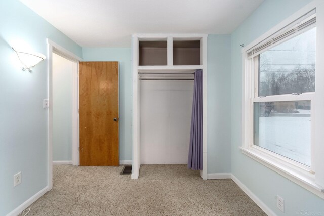 unfurnished bedroom with light carpet and a closet