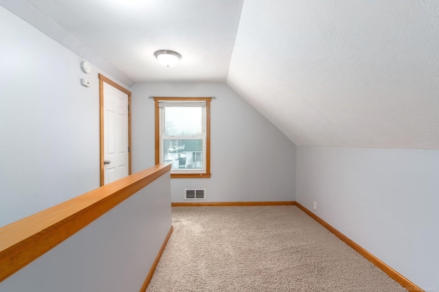 bonus room featuring lofted ceiling, light carpet, and a textured ceiling