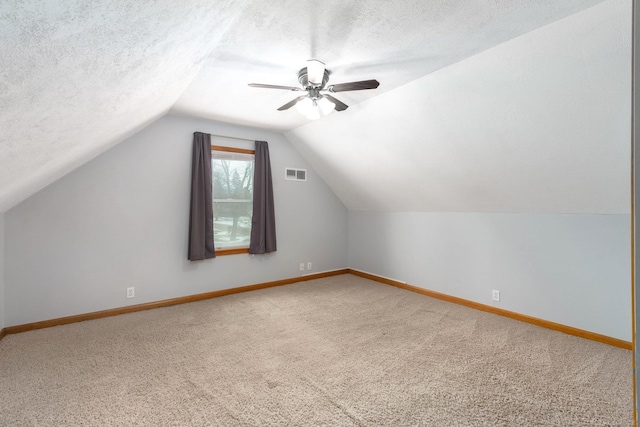 additional living space with ceiling fan, lofted ceiling, carpet, and a textured ceiling