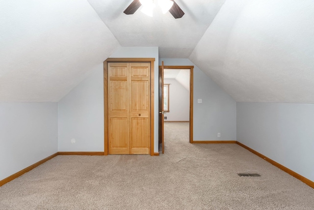 bonus room featuring lofted ceiling, light colored carpet, a textured ceiling, and ceiling fan