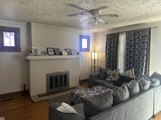 living room featuring hardwood / wood-style flooring, ceiling fan, a textured ceiling, and a fireplace