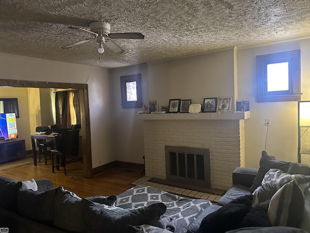 living room with hardwood / wood-style flooring, plenty of natural light, a textured ceiling, and a brick fireplace