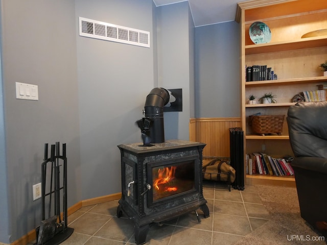 sitting room with tile patterned floors and a wood stove