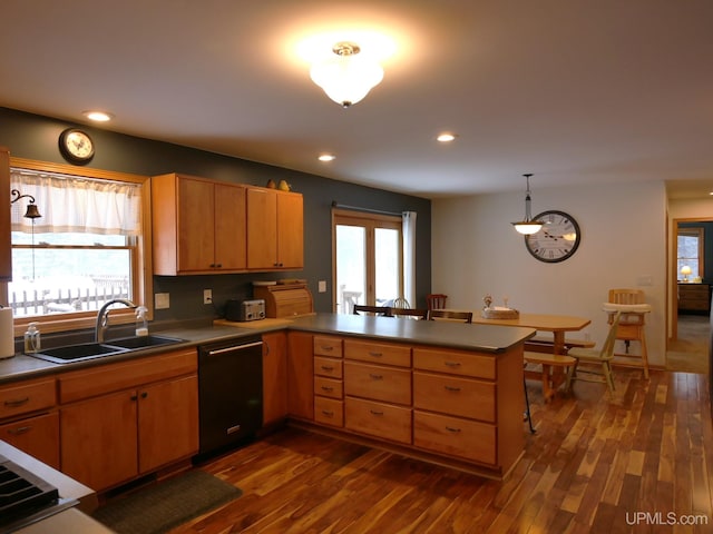 kitchen featuring pendant lighting, dishwasher, sink, kitchen peninsula, and dark wood-type flooring