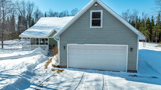 snow covered property featuring a garage and covered porch