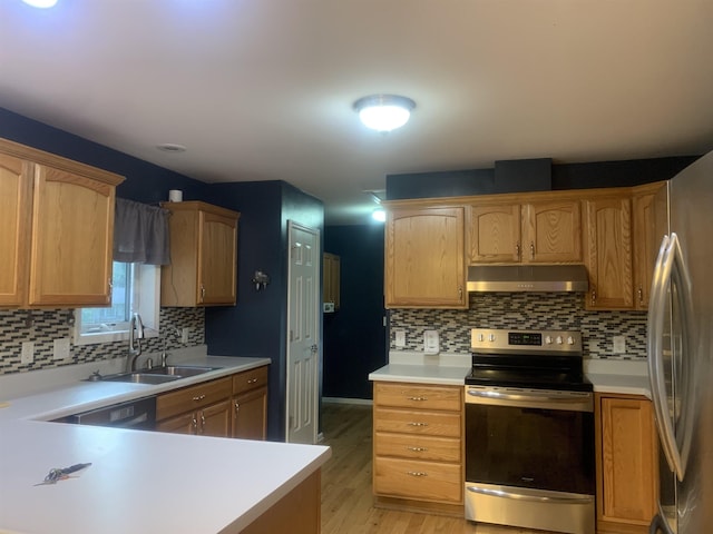 kitchen with tasteful backsplash, appliances with stainless steel finishes, sink, and light wood-type flooring